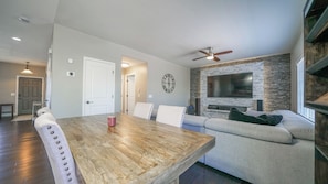 A modern living room with a wooden dining table, a gray sofa, and a stone accent wall.