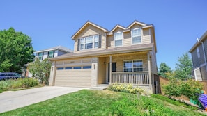 A two-story residential house with a garage, a front porch, and a well-maintained lawn.