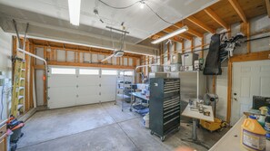 A spacious garage with a concrete floor, wooden beams, and a workbench with tools. - Beautiful 3 bedroom home with theater! (Littleton)