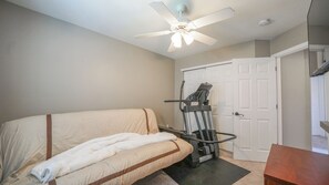 A room with a bed, a ceiling fan, a treadmill, and a door. - Beautiful 3 bedroom home with theater! (Littleton)