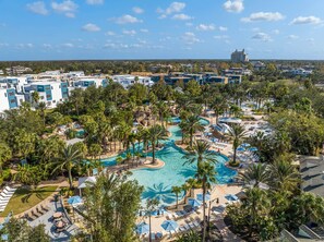 Un resort con una piscina central rodeada de palmeras y tumbonas.