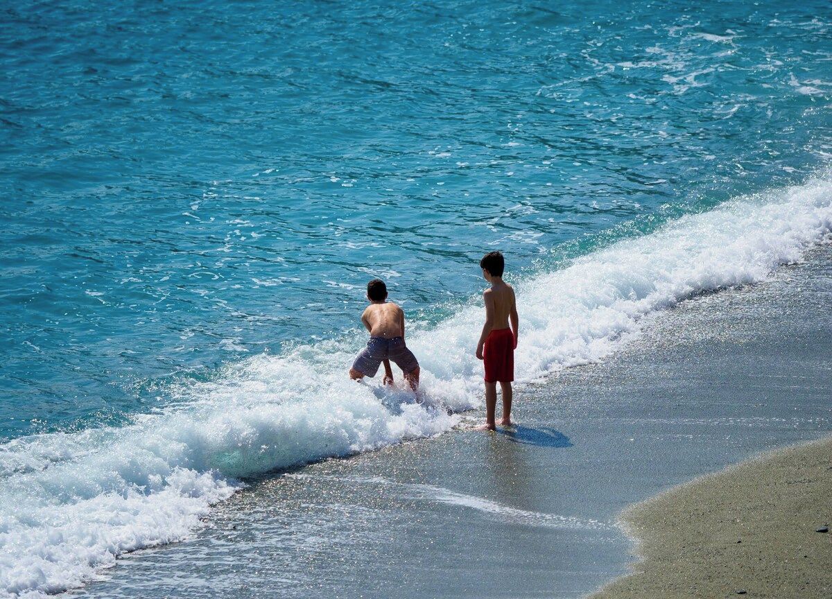 Dos personas en la playa mientras las olas se acercan.