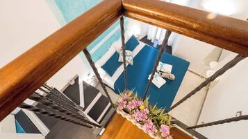Eine Holzt Treppe mit Metallgeländer, einem blau teppichbesetzten Bereich und einer Blumenkomposition am unteren Ende.