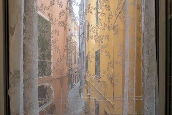 Una finestra amb un dibuix floral i un edifici groc a l'exterior.