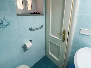 A bathroom with a toilet, a towel rack, and a toilet paper holder on the wall. - Picagetta Tiny Room with AC (Vernazza)