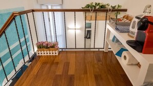 A wooden staircase with a white picket fence, a wooden floor, a white wall, a white ceiling, and a red appliance on the right. - Picagetta Tiny Room, one of the smallest and most comfortable rooms in Vernazza (Vernazza)