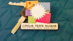 A set of keys, a nameplate, and colorful cards on a textured surface. - Picagetta Tiny Room, one of the smallest and most comfortable rooms in Vernazza (Vernazza)