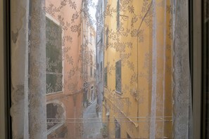 Janela com padrão floral e um edifício amarelo lá fora.