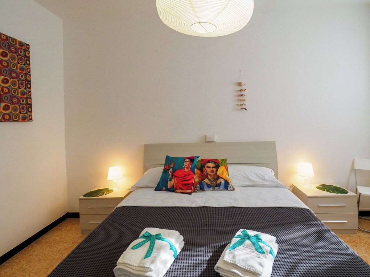 Ein Hotelzimmer mit einem Bett, zwei Nachttischen mit Lampen, einem Wandbild und einer dekorativen Hängeleuchte.