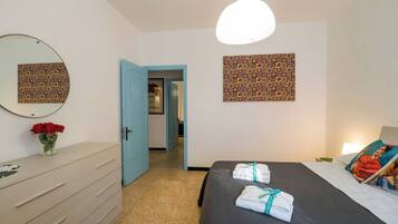 Une chambre d’hôtel comprenant un lit, une commode, un miroir et une porte donnant sur une autre pièce.