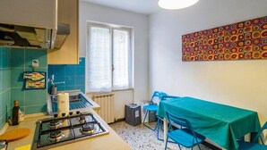 Une cuisine de taille réduite, équipée d’une cuisinière à gaz, d’une fenêtre et d’une table avec des chaises.