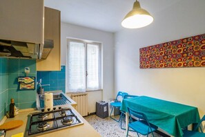 Une cuisine de taille réduite, équipée d’une cuisinière à gaz, d’une fenêtre et d’une table avec des chaises.