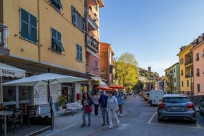 Straatbeeld met gebouwen, terrasjes en geparkeerde auto's.