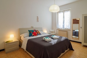 A neatly arranged hotel room with a bed, bedside table, lamp, and a window with curtains. - La Casa di Frida 2 bedroom Apartment (Vernazza)