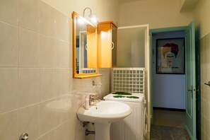 Een badkamer met een wit wastafelmeubel, spiegel en betegelde wanden.