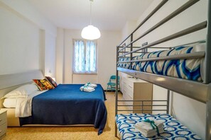 Une chambre de dortoir avec des lits superposés, un lit simple, un bureau et une fenêtre avec des rideaux.