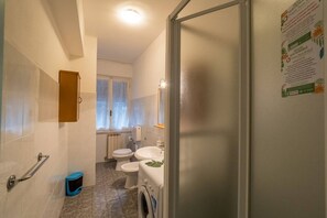 Une petite salle de bain comprenant des toilettes, un bidet et un lave-linge.