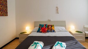 Een hotelkamer met een bed, twee nachtkastjes, een kunstwerk aan de muur en een plafondlamp.