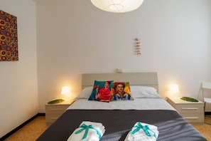 A hotel room with a bed, two bedside tables, a wall art piece, and a ceiling light fixture.