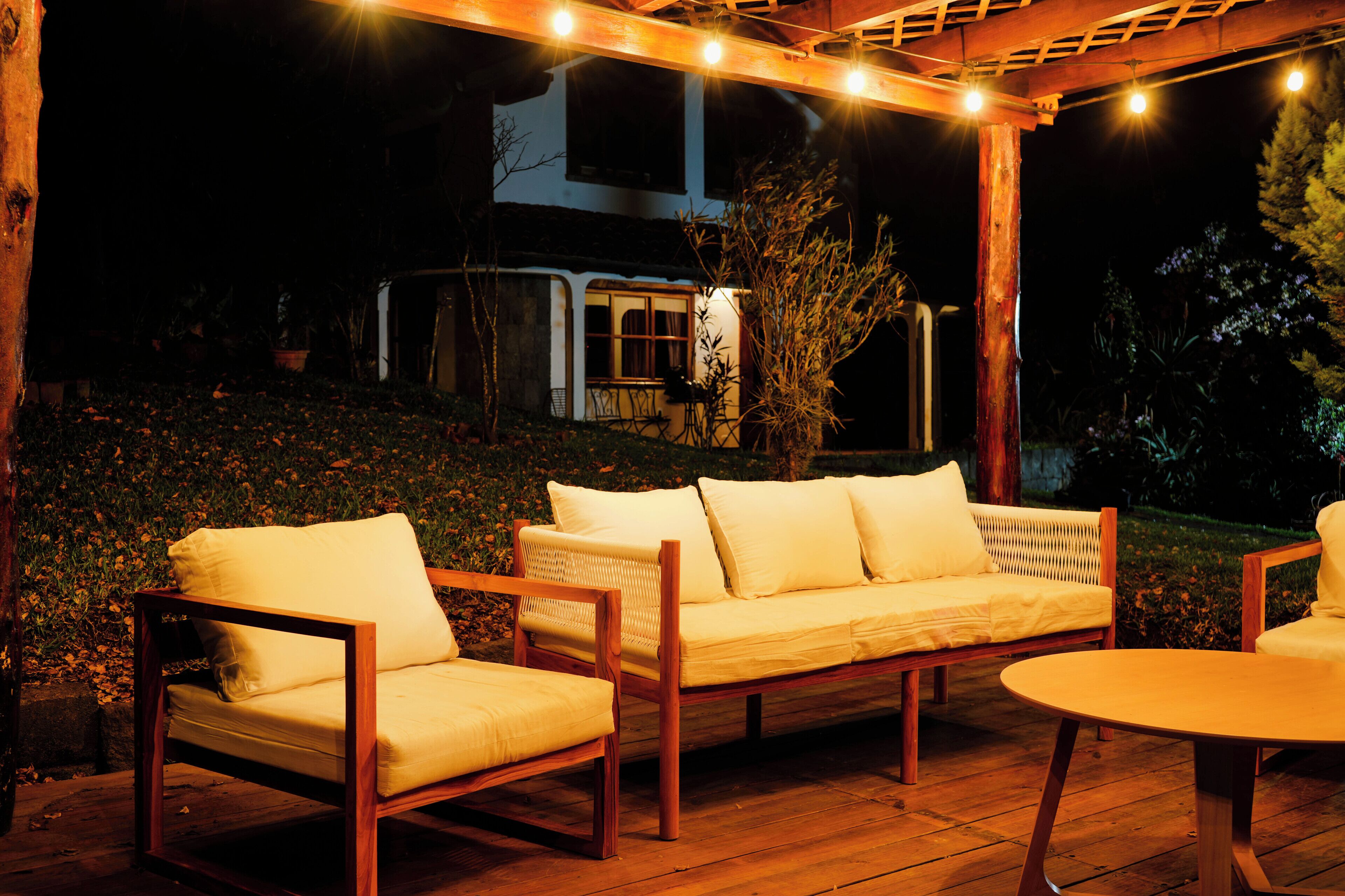 Een terras buiten met houten meubels en een tafel, omringd door een houten terras en een tuin.