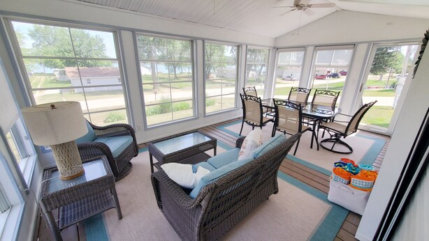 A sunroom with wicker furniture, large windows, and a view of the outdoors. - Silver Lake - 4th of July - Lake Access - MIS (Addison)