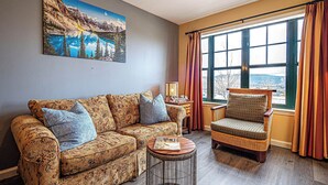 A living room with a sofa, armchair, and a round coffee table. - Mountain Creek Lovely 1 Bedroom/Pool/Jacuzzi/King Bed/Ski In/Out (Vernon Township)