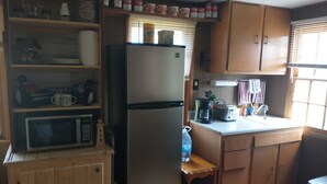 A compact kitchen with wooden cabinets, a refrigerator, a microwave, a toaster, and a sink. - Quaint cozy little cabin geared for folks coming to Leech Lake to fish or relax. (Federal Dam)