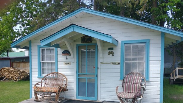 A small, single-story house with a blue trim and a porch. There are two wicker chairs on the porch. - Quaint cozy little cabin geared for folks coming to Leech Lake to fish or relax. (Federal Dam)