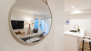 A modern kitchen with a white countertop, a sink, and a small bar stool.