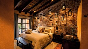 Un dormitorio acogedor con pared de piedra, una cama grande, un banco de madera y faroles en la pared.