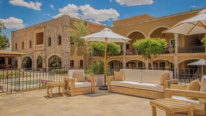 Un patio con mobiliario exterior, una fuente y un edificio con arcos.