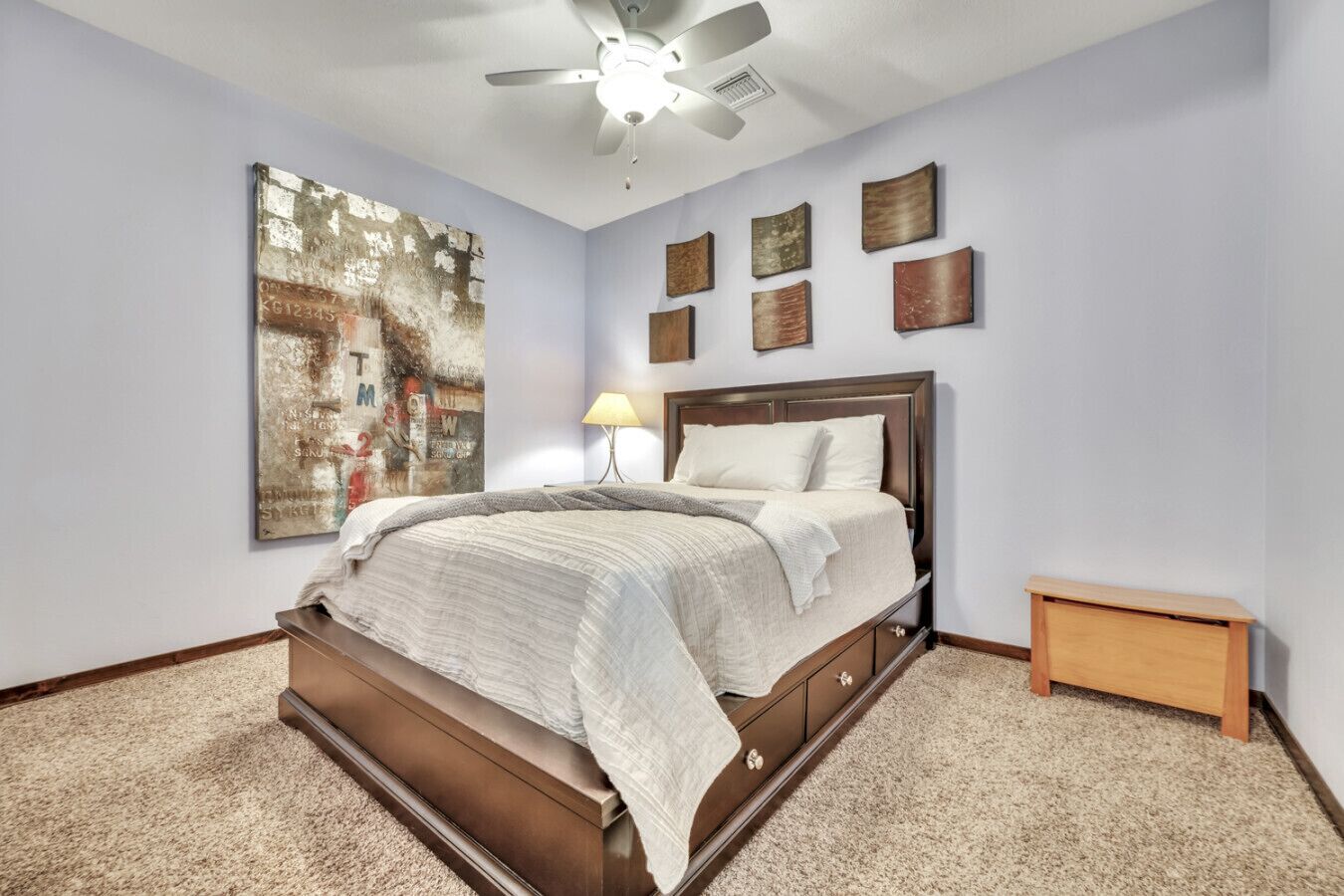 Une chambre avec un grand lit, un ventilateur de plafond et une table de chevet.
