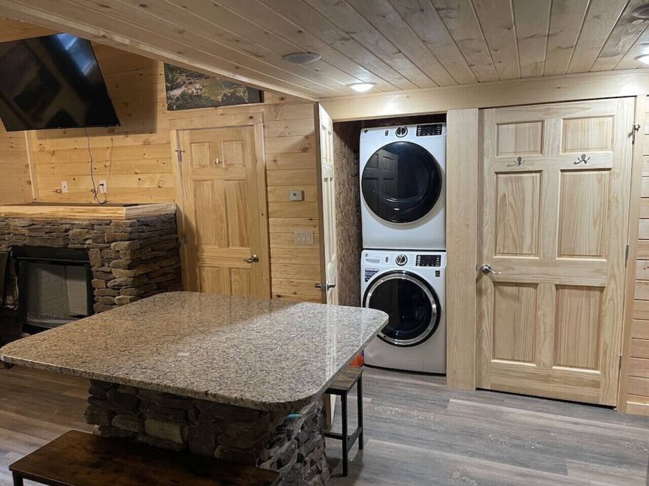Una cucina con piano di lavoro in granito, camino in pietra, mobili in legno e lavatrice.