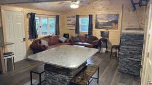 Ein gemütliches Blockhauss-Interieur mit einer Steinservierinsel, Holzwänden, einem Ledersofa und einer Wand mit Steindekor.