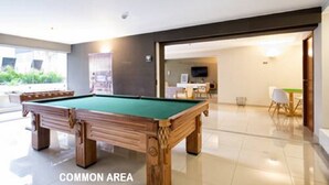 A pool table in a common area with a modern design, a dining table with chairs, and a television in the background. - BEST LOCATION BALCONY! MIRAFLORES HEART 1BD/1.5BA (Miraflores)