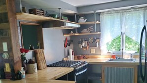 Een keuken met houten vloer, een fornuis, een spoelbak en een raam met gordijnen.