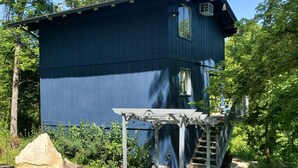 Een blauw huis met een overdekte veranda en een pad van stenen dat er naartoe leidt.