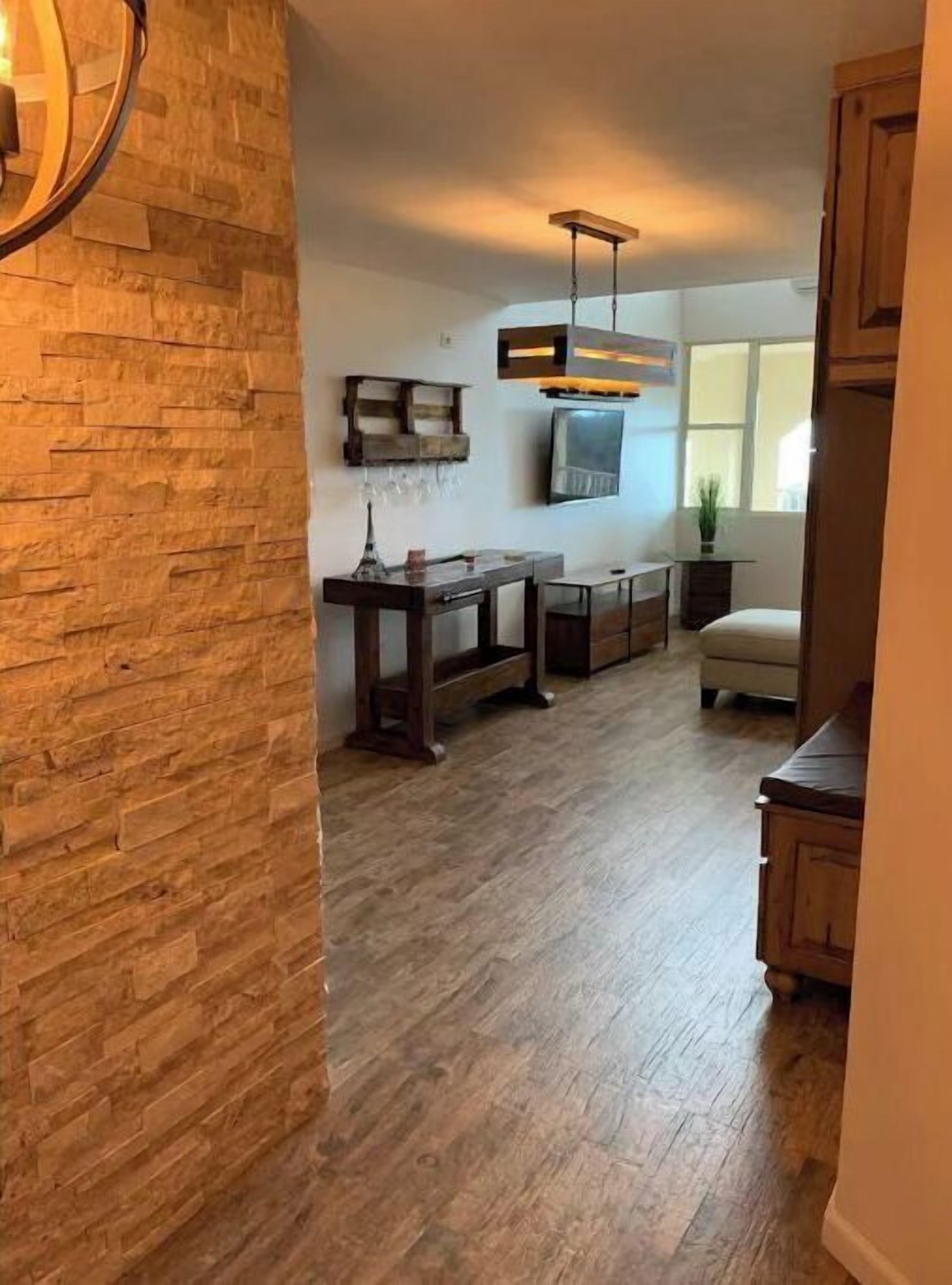 A modern kitchen with wooden flooring, a built-in bench, and a hanging light fixture.