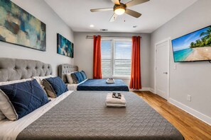 Ein Schlafzimmer mit zwei Betten, einem Deckenventilator und einem großen Fenster mit Vorhängen.