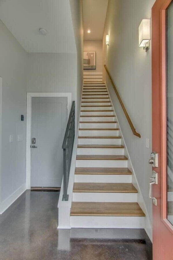 Un escalier avec des marches en bois et une rampe, menant à une porte située en haut.