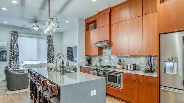 Una cocina moderna con gabinetes de madera, una isla grande y electrodomésticos de acero inoxidable.