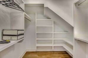 Un interior moderno y luminoso, con suelo de madera, una escalera blanca y estanterías empotradas.