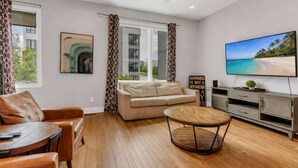 Una sala de estar moderna con sofá, mesa de centro, televisor y vista al mar a través del ventanal.