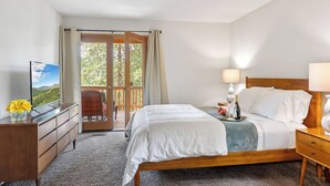 A bedroom with a bed, a desk, a TV, and a balcony with a chair.