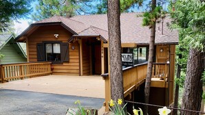 A lodge with a covered deck, a front entrance, and a sign indicating the name and address.