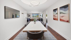 A modern dining area with a long table, chairs, a hanging light fixture, and artwork on the walls. - Summit Lofts, Extra Large Executive Suite, #210 (Mt. Shasta)