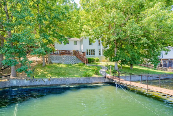 A house with a wooden deck and a small pond in front.