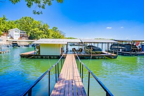 A wooden dock leading to a marina with boats and a covered area.