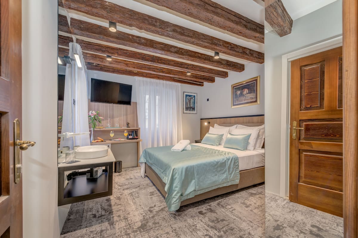 A bedroom with a bed, bedside table, and a wooden door.