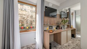 A modern hotel room with a wooden desk, a flat-screen TV, and a window with curtains. - Makarun Heritage Rooms (Split)